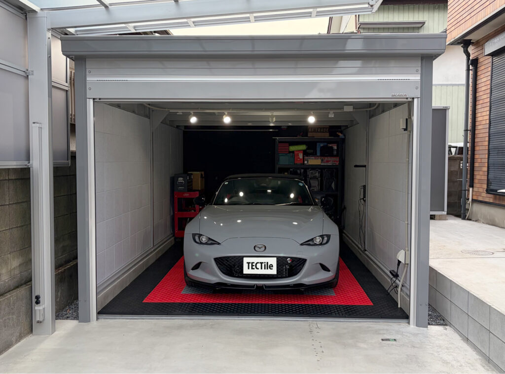赤と黒のテックタイルを敷いたガレージと車